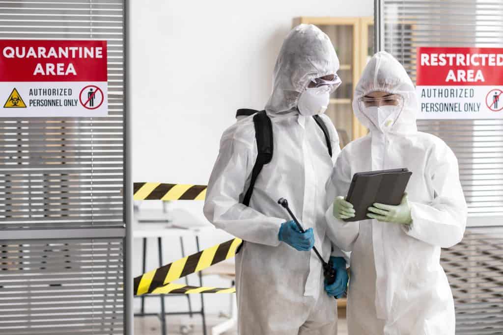 personnes en equipement de protection desinfectant une zone dangereuse